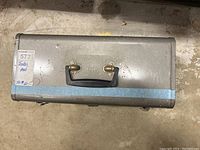 Top view of closed metal Craftsman toolbox with handle and latches visible showing wear and blue tape at bottom
