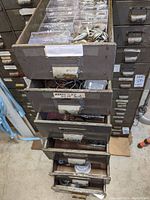 Six metal drawers stacked containing various washers and metal fasteners in plastic compartments.