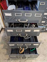 Four open metal drawers showing organized trays of sockets, ratchets, and assorted tools, some handwritten drawer labels visible.