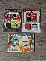Front side of 3 Panini NFL jersey cards featuring Trey Sermon, Kyle Trask, and Jaylen Waddle with visible fabric swatches