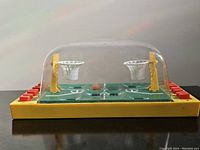 Front view of the vintage tabletop basketball game in a clear dome showing the basketball court, hoops, and player controls.