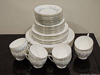 Stacked plates and cups showing size gradation and floral silver design