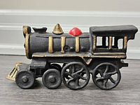 Side view of the cast iron train showing black body with gold and red accents.