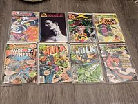 All 8 vintage comic books laid out showing covers featuring various superheroes and characters