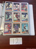 Binder open to a page showing nine hockey cards in a 3x3 layout