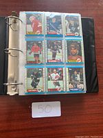 Photo showing an open binder page with nine hockey cards visible in protective sleeves. Cards feature players in various team uniforms.