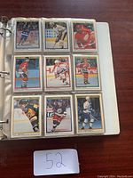 Page of a binder with nine hockey cards in plastic sleeves showing various NHL players in action on ice.