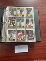 Binder open to a page showing nine hockey cards in clear plastic pockets