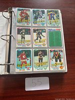 Binder open to a page showing nine hockey cards in clear sleeves under natural light