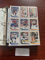 Open binder page showing 9 hockey cards featuring various players in game action, arranged in a 3x3 grid inside plastic sleeves.