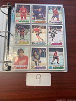 Open binder page showing nine hockey cards of various players in team uniforms.