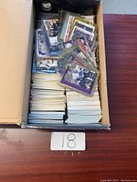 Photo of a cardboard box filled with numerous hockey cards stacked inside. Some cards are individually sleeved in plastic.