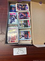 Box shown from above with multiple stacks of hockey cards in varying conditions featuring different players and teams.