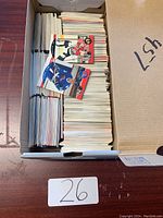 Top-down view of a large box filled with numerous loose hockey cards, some arranged vertically and a few cards placed on top showing different player images.