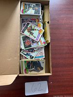 Overhead shot of cardboard box filled with hockey cards on wooden table.