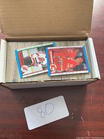 Box of hockey cards with cards stacked inside and two cards facing up on top showing hockey players in team uniforms.