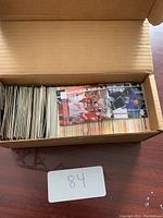 Photo showing an open box filled with a large number of hockey trading cards packed together vertically with some cards facing up displaying colorful images and text.