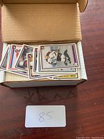 Photo of an open cardboard box filled with numerous hockey trading cards, showing colorful cards with player images and team logos.