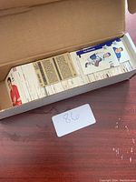 Open cardboard box filled with a large collection of hockey cards, some cards partially visible showing players in sports uniforms.