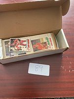 Open box showing multiple stacks of hockey cards arranged inside on a wooden surface with a lot card number.