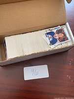 Open cardboard box filled with hockey trading cards mostly sleeved, with a few visible cards on top.