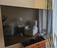 Front view of TV powered off on wooden stand showing design and size
