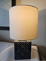 Front view of the lamp showing the white fabric shade and blue base with white diamond pattern.