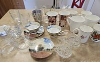 Overview of all items showing porcelain cups and saucers, assorted mugs, glass bowls, toothpick holders, and servers arranged on table.
