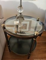 Top view of the round side table showing glass top, gold accent knobs on legs, and candle on top.