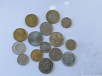 Photo showing 15 assorted coins of different sizes and metals laid out on a flat surface