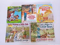 Set of five children's bible and Christian-themed books arranged in two rows on a white surface.