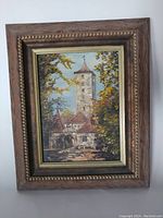 Front view of the framed oil painting showing the stone tower with surrounding buildings and autumn foliage.