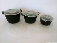 Set of three Pampered Chef microwave steamers shown side-by-side with their translucent lids on and the large steamer insert visible.