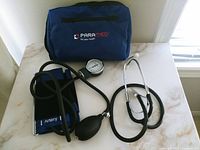 Full medical kit contents displayed on surface including blue ParaMed carrying pouch, manual blood pressure cuff with gauge and inflation bulb, and stethoscope.