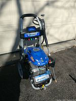Front-angled view of assembled pressure washer showing frame, engine housing, wand mount and wheel base
