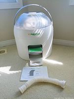 Front view of Yirego Drumi portable non-electric washing machine showing body, handle, and foot pedal with instruction manual and hose extension in front.