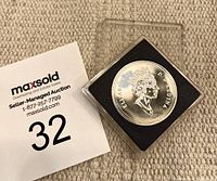 Photo showing the coin in its clear plastic display case, highlighting the uncirculated condition and presentation.