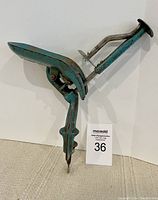 Blue antique double cherry pitter clamp-on device with lever and dual pitting rods shown from side angle.