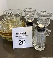 Nine assorted glassware pieces including two clear crystal candle holders, five different glass bowls with various textures and one amber bowl, and a pair of vintage salt and pepper shakers with used tops.