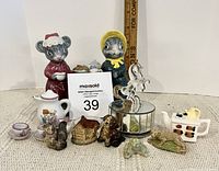Front view of assorted children's decor bits and miniatures on white surface with ruler for scale.