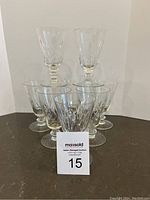 Photo showing 7 clear vintage cut crystal wine glasses in a group, each with a stem and intricate cut pattern.