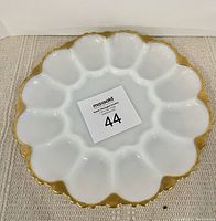 Top view of white glass deviled egg plate showing round egg compartments with gold scalloped edge trim