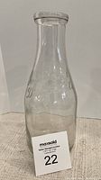Front view of clear glass vintage milk bottle showing embossed company text and bottle shape