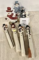 Seven assorted snowmen figurines arranged on fabric background