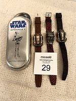 Photo of three Star Wars Episode I collectible watches and the original metal tin. The watches have character face covers that open to show digital displays. The tin is labeled with Star Wars Episode I and Battle Droid.