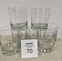 Eight clear heavy-bottomed whiskey glasses arranged with a MaxSold auction tag in front of them.