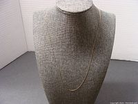 Full view of the delicate 10K gold necklace displayed on a bust, showing the chain length and fine links.