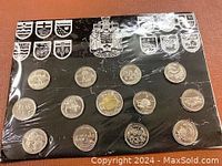 Photo showing 14 Canadian coins arranged on a black card with provincial shields and the Canadian coat of arms in silver.
