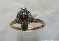 Front view showing central ruby, surrounding seed pearls and peridot stones