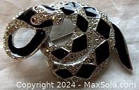 Close-up photo of the vintage snake brooch showing the detailed head with red rhinestone eyes and alternating black enamel and clear crystal rhinestones on the body.